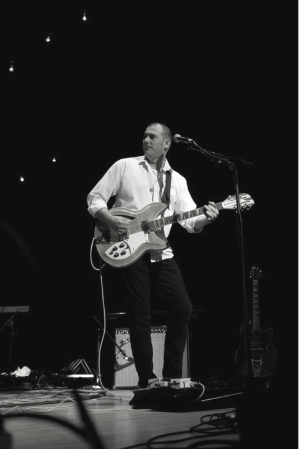 Dan Greunke performing on a stage with a guitar