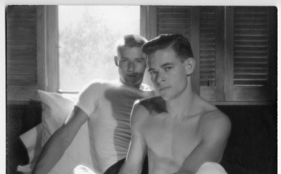 Two men posed on a bed